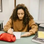 Studentka przygotowuje się do egzaminu w sali wykładowej z notatkami