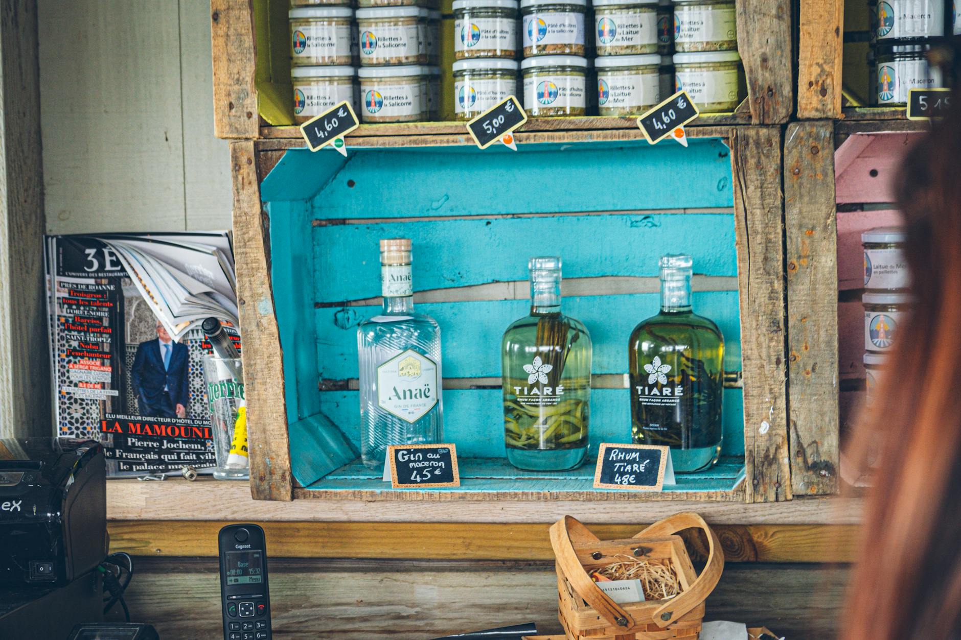 Butelki ginu i rumu na rustykalnej drewnianej półce z cenami