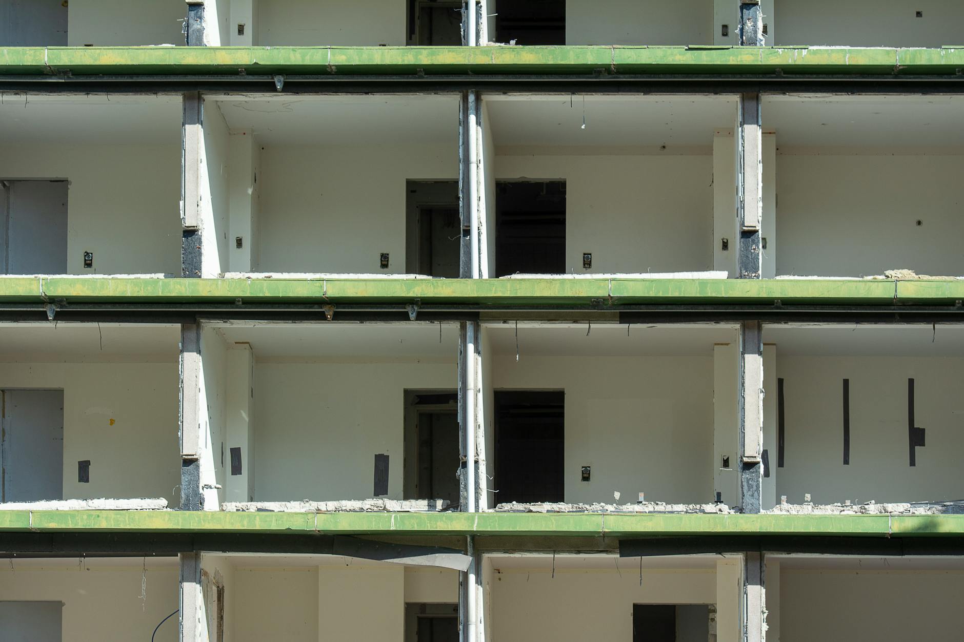 Częściowo zburzony budynek z odsłoniętym betonowym stropem i pustymi mieszkaniam