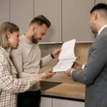 Co może deweloper a czego nie wolno mu obiecywać w reklamach inwestycji Para z agentem przegląda dokumenty zakupu mieszkania w biurze dewelopera
