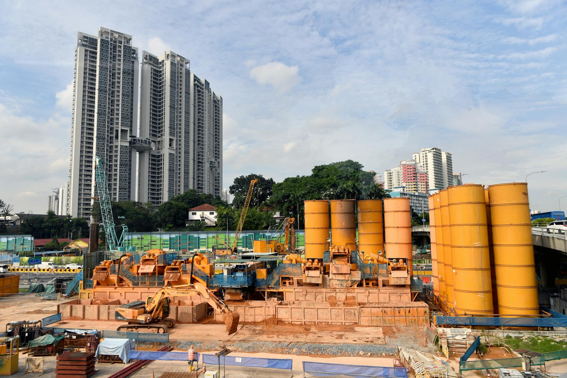 Plac budowy z żółtymi maszynami na tle miejskich wieżowców