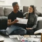 Uśmiechnięta para planuje wystrój mieszkania wśród kartonów i próbek farb