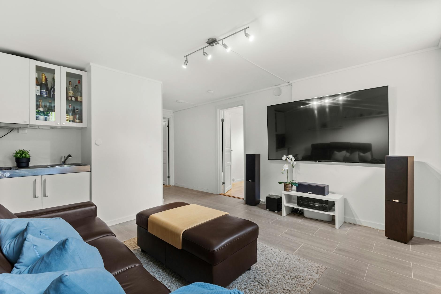 Jasny salon na wynajem z dużym telewizorem i skórzaną sofą