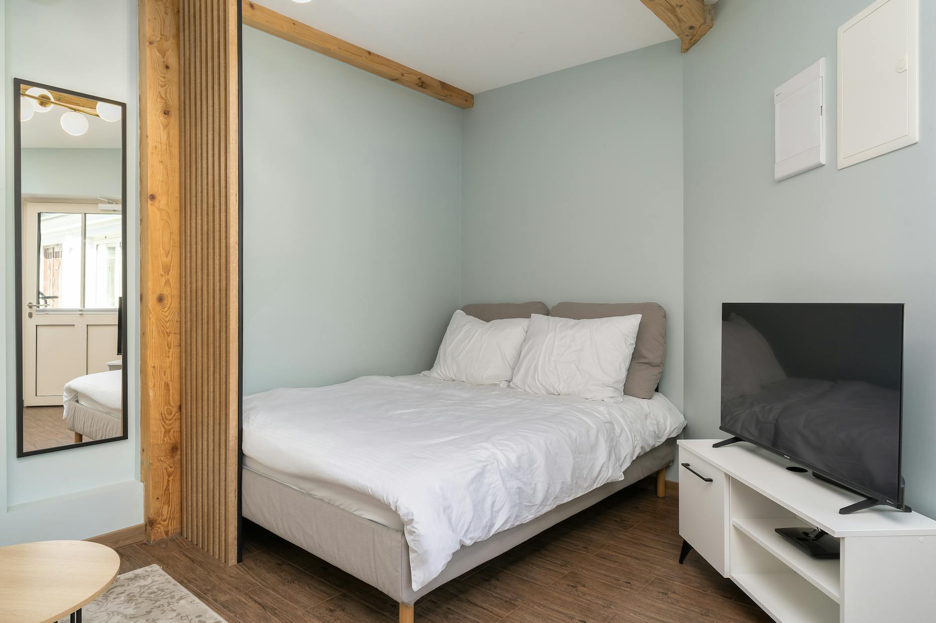 Minimalistyczna sypialnia w mieszkaniu na wynajem z łóżkiem i telewizorem