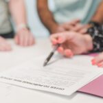 Zbliżenie dłoni podpisujących ofertę zakupu mieszkania i analizujących dokumenty